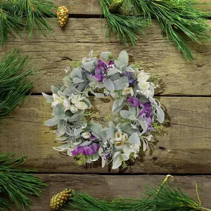 Detail of lavender and cream wreath with flocked green leaves on a rustic wood surface