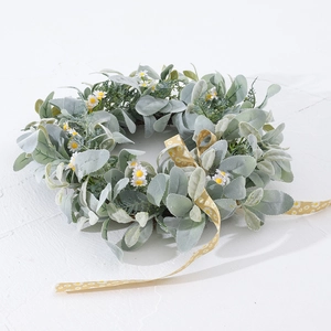 Détail d'une couronne de marguerites artificielles avec feuilles et ruban jaune