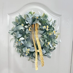Détail d'une couronne de marguerites blanches avec ruban jaune sur une porte en bois