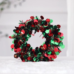 Close-up of green tinsel Christmas wreath with shiny red and green metallic sequins