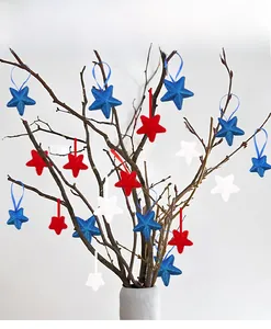 Detail of red white and blue glittery star ornaments hanging on branches in a vase