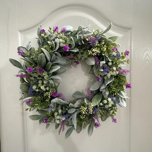 Close-up of artificial lavender wreath with flocking green leaves on a white door