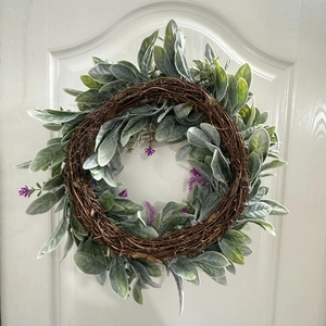 Close-up of artificial lavender wreath with green leaves on a white wooden door