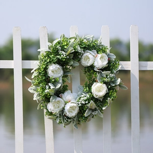 Artificial white peony wreath with eucalyptus leaves on a white fence for garden decor