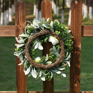 Artificial white peony wreath with eucalyptus leaves on a natural rustic rattan base