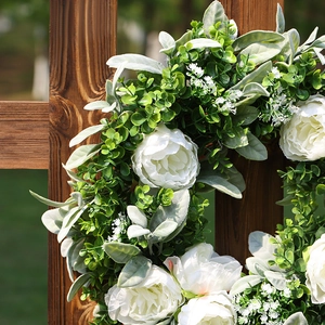 Artificial white peony and eucalyptus wreath hanging on a rustic brown wooden fence