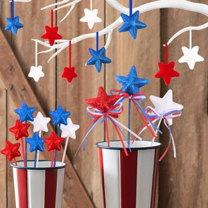 Patriotic July 4th star ornaments with red white blue glitter star sticks in rustic bucket