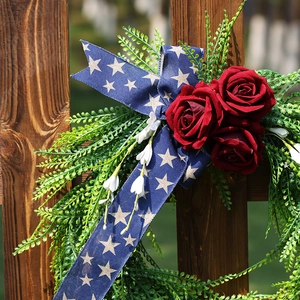 Patriotic USA wreath with red roses and blue star ribbons on a rustic wooden fence