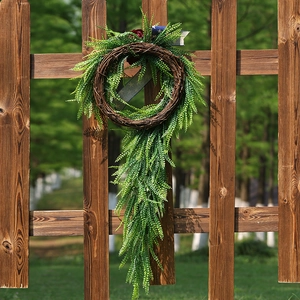 Patriotic wreath with American flag ribbon and greenery on a wooden fence