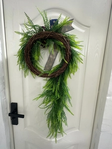 Detail view of Independence Day themed wreath with green leaves on a white door
