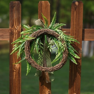 Rustic artificial fern wreath on wooden fence with burlap bow for home garden decor