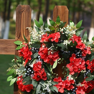 Couronne de fleurs rouges artificielles avec feuilles vertes sur clôture en bois