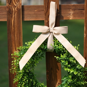 Artificial eucalyptus wreath with a burlap bow hanging on a dark wood garden fence
