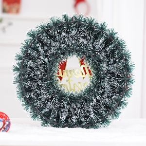 Ghirlanda di Natale con aghi di pino innevati, scritta dorata Merry Christmas e fiocco rosso