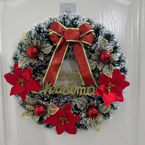 Dettaglio ghirlanda natalizia artificiale con fiocco rosso e scritta Merry Christmas