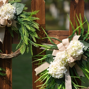 Garden farmhouse wreath with white hydrangeas and rustic burlap bow on wooden fence