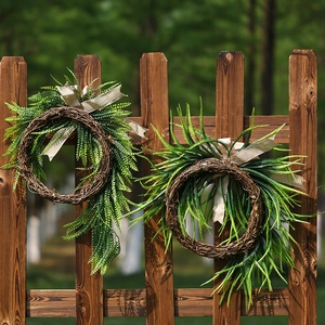 Artificial fern wreath set with burlap bows on a rustic wooden fence for garden decor