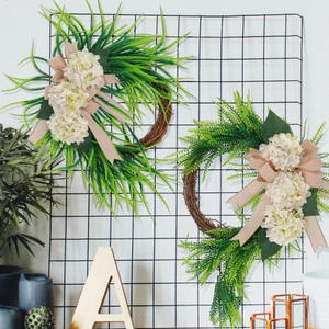 Detail showing artificial white hydrangea wreaths with burlap bows on a wire rack