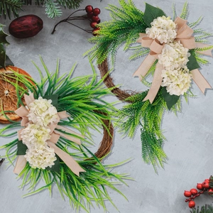 Detail of farmhouse wreath with white hydrangea, green ferns and a burlap bow on grapevine
