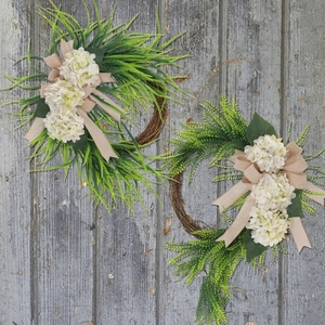 Detail of farmhouse wreath featuring white hydrangeas, green ferns and burlap bow