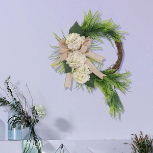 Close-up of white hydrangea wreath with green fern leaves and a rustic burlap bow