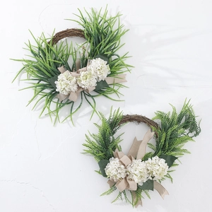 Detail of farmhouse wreath featuring white hydrangeas and rustic burlap bow on vine base