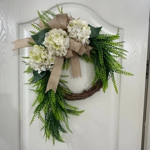 Detail of farmhouse wreath with white hydrangeas, burlap bow and natural vine base