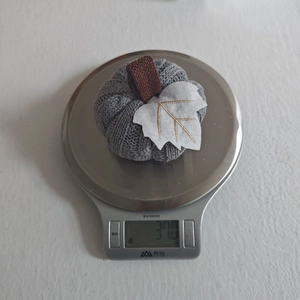 Detail of grey knitted pumpkin decoration being weighed on an electronic kitchen scale