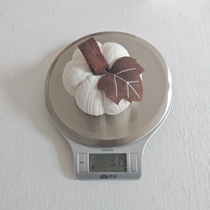Knitted pumpkin ornament showing weight of 31.5g on a silver digital scale