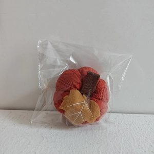 Close-up of a handmade knitted orange pumpkin decor packed in a clear OPP plastic bag