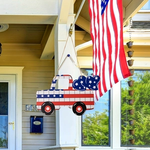 Detail of wooden American flag truck door hanger with blue heart bells on house porch