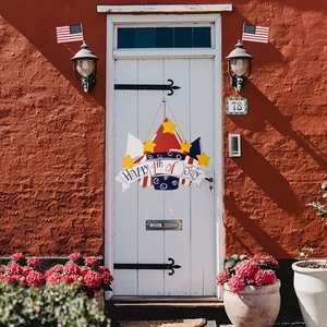 Close-up of wooden Happy 4th of July door sign hanging on white door with festive flags