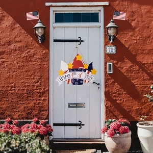 Detail of wooden Happy 4th of July door sign hanging on a white door with American flags