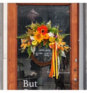 Detail of harvest wreath with sunflowers and pumpkin on a vintage wooden glass door