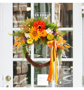 Detail of harvest wreath with sunflowers, pumpkins and ribbons on a white door