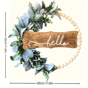 Detail showing artificial eucalyptus leaves and wooden beads with a hello sign wreath