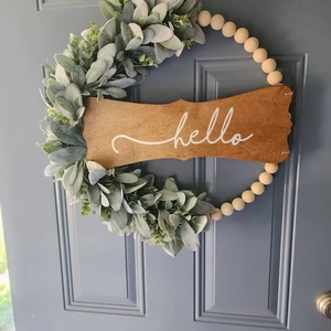 Detail of wooden bead wreath with hello sign and green leaves on a blue door