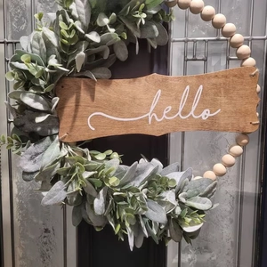Detail of wooden bead wreath with eucalyptus leaves and white hello wooden sign
