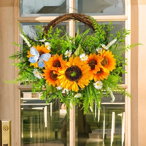 Ernte-Sonnenblumenkranz mit grünen Blättern und blauem Schmetterling an Holztür