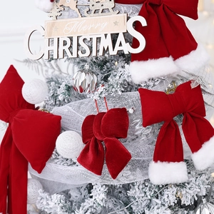 Large red velvet Christmas bow with white faux fur trim on a decorated festive tree