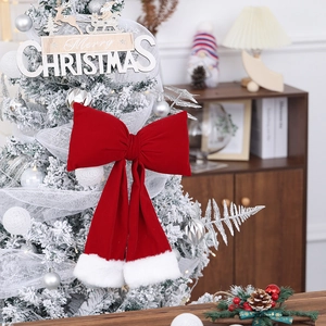 Detail view of a large red velvet Christmas bow with white faux fur trim on a tree