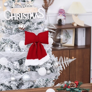 Detail of red velvet Christmas bow with white faux fur trim on a flocked tree branch