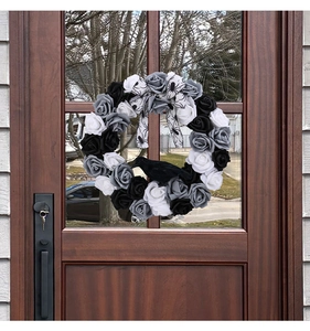 Detail of Halloween wreath with black roses, a crow model and a spiderweb bow on a door