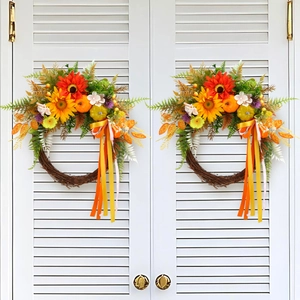 Pair of autumn harvest wreaths with pumpkins and sunflowers on white shutter doors