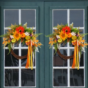 Autumn harvest wreath with sunflowers and pumpkins on dark vintage glass doors