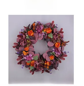 Detailed close-up of autumn wreath with orange roses, purple peonies and red eucalyptus leaves