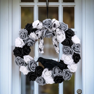 Halloween deurkrans met zwarte en witte rozen, zijden strik en kunstmatige kraai
