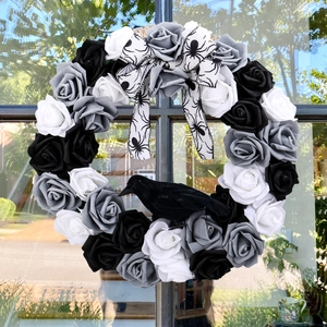 Halloween krans met zwart-witte rozen, kraaimodel en spinnenzijde lint op de deur
