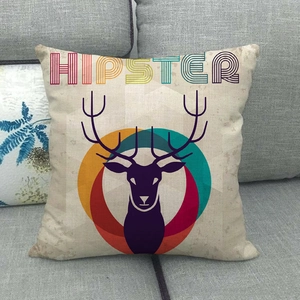 Detail of linen cushion cover with geometric deer head print on a grey fabric sofa
