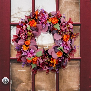 Autumn wreath with faux peonies and hydrangeas hanging on a red wooden door